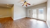 Located at 100 Portico St in Lynchburg, Virginia, this well-appointed single-story home offers three bedrooms, two bathrooms, and a thoughtfully designed layout across a comfortable footprint. The open-concept living, dining, and kitchen area serves as the heart of the home, featuring warm wood-look flooring, recessed lighting, and a ceiling fan that enhances air circulation throughout. The kitchen stands out with rich dark wood cabinetry, granite countertops, stainless steel appliances, and an oversized peninsula with pendant lighting — ideal for both cooking and casual dining. A pantry provides additional storage convenience. The living area opens directly to a private balcony through elegant French doors, allowing natural light to pour in. The bedrooms are carpeted for comfort and each includes a ceiling fan and window with blinds. The primary bedroom offers a generous walk-in closet with wire shelving on both sides. Additional closets throughout the home provide ample storage. The bathrooms are clean and functional, featuring a tub/shower combo with oil-rubbed bronze fixtures. A dedicated utility room rounds out the practical layout. Neutral tones and consistent finishes create a cohesive, move-in-ready aesthetic throughout.