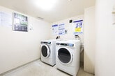Located at 3201 Lawrence Ave E in Toronto, this shared laundry room is a compact, single-floor utility space designed to serve building residents efficiently. The room features light-coloured walls and a terrazzo-style tile floor, giving it a clean and functional appearance. Overhead ventilation is provided through a ceiling-mounted vent, and lighting is distributed evenly throughout the space.

The room is equipped with Maytag commercial-grade front-loading washing machines and dryers, positioned along one wall for easy access. A double utility sink with exposed faucet fixtures is available for hand-washing or pre-treating garments. A coin or card-operated payment system is installed on the wall, and the room also supports a mobile payment option, as indicated by posted signage.

Informational posters and instruction sheets are prominently displayed on the walls, covering washer and dryer operating procedures, dryer safety guidelines, and laundry room usage rules. These resources ensure residents can operate the machines correctly and safely. A waste bin is also present for basic housekeeping. The room is accessed through a solid white door. Overall, the space is straightforward, well-organized, and purpose-built to provide a practical laundry facility for the building's residents.