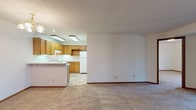 This single-floor residence offers a practical and well-organized layout designed for comfortable everyday living. The open-concept living and kitchen area forms the heart of the space, where a peninsula counter separates the two zones while maintaining a sense of openness. The kitchen is equipped with warm oak cabinetry extending to the upper and lower walls, white appliances including a coil-top electric range, double-basin sink, and refrigerator, all set against light countertops and tile flooring. A textured ceiling and flush fluorescent lighting illuminate the kitchen, while a chandelier adds a touch of warmth to the living area, which features neutral wall-to-wall carpeting throughout.

The bedrooms are generously sized, each carpeted and featuring windows with blinds that invite natural light. One bedroom includes a closet with sliding doors, providing practical storage. The two bathrooms are finished with light-toned cabinetry, wide vanity countertops, large mirrors with overhead lighting, and tile flooring. The overall aesthetic is clean and neutral, with consistent wood-toned trim accents, textured ceilings, and a straightforward design that offers a functional and move-in-ready living environment.