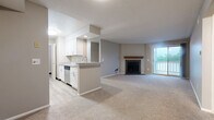 Located at 1660 Seabreeze Ct in Dayton, Ohio, this well-appointed two-bedroom, two-bathroom residence offers a thoughtfully designed single-floor layout. The open-concept living and kitchen area serves as the heart of the home, where light-toned carpet flows through a generously sized living room anchored by a tile-surround fireplace with a wood mantel. A sliding glass door leads to a private balcony, filling the space with natural light. The galley-style kitchen features white shaker cabinetry, granite-look countertops, a breakfast bar peninsula, stainless steel appliances including a range and dishwasher, and light wood-look flooring. Both bedrooms are carpeted and offer natural light through large windows, with the primary bedroom providing a comfortable and private retreat. The bathrooms are finished with granite-look vanity tops, white cabinetry, tile-surround tub-shower combinations, and wood-look vinyl flooring. A dedicated laundry room with wire shelving adds everyday convenience, while three closets throughout the unit provide ample storage. Neutral tones and consistent finishes create a clean, cohesive aesthetic across the entire residence.