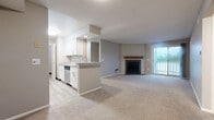 Located at 1660 Seabreeze Ct in Dayton, Ohio, this well-appointed two-bedroom, two-bathroom residence offers a thoughtfully designed single-floor layout. The open-concept living and kitchen area serves as the heart of the home, where light-toned carpet flows through a generously sized living room anchored by a tile-surround fireplace with a wood mantel. A sliding glass door leads to a private balcony, filling the space with natural light. The galley-style kitchen features white shaker cabinetry, granite-look countertops, a breakfast bar peninsula, stainless steel appliances including a range and dishwasher, and light wood-look flooring. Both bedrooms are carpeted and offer natural light through large windows, with the primary bedroom providing a comfortable and private retreat. The bathrooms are finished with granite-look vanity tops, white cabinetry, tile-surround tub-shower combinations, and wood-look vinyl flooring. A dedicated laundry room with wire shelving adds everyday convenience, while three closets throughout the unit provide ample storage. Neutral tones and consistent finishes create a clean, cohesive aesthetic across the entire residence.