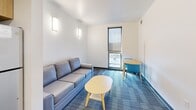 Located at 304 College Ave in Ithaca, NY, this one-bedroom unit offers a compact, efficiently organized layout spread across a single floor. The design prioritizes function, making smart use of every area throughout the space.

The kitchen is outfitted with stainless steel appliances, including a refrigerator, electric range, over-the-range microwave, and dishwasher. Light wood cabinetry lines the upper and lower walls, providing ample storage, while dark granite-style countertops add a clean, modern contrast. Light vinyl plank flooring extends through the kitchen and entry area, offering durability and easy maintenance.

The living room features patterned blue-gray carpeting, wall-mounted sconce lighting, and a window that allows natural light to enter. The layout accommodates a sofa and small dining table, making it a functional shared space for both relaxing and dining.

The bedroom is a comfortable, well-defined space with carpeted flooring, a window with a roll-down shade offering outdoor views, and sufficient room for a bed and desk setup — practical for studying or working.

The entry foyer is clean and minimal, with light flooring and direct access to the kitchen area. Throughout the unit, the design is contemporary and straightforward, with white walls and modern finishes creating a cohesive, no-frills aesthetic.