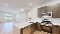 Located at 100 Shepherds Ln in Totowa, NJ, this thoughtfully designed 2-bedroom, 3-bathroom residence offers a clean, modern aesthetic throughout its single-floor layout. Light hardwood flooring flows seamlessly through the living spaces, complemented by crisp white walls and recessed lighting that create a bright, airy atmosphere.

The kitchen is a standout feature, showcasing warm wood-toned cabinetry with matte black hardware, a striking quartz countertop with subtle veining, and a full suite of stainless steel appliances including a gas range, built-in microwave, dishwasher, and refrigerator. A peninsula with an undermount sink adds both workspace and a natural gathering point connecting the kitchen to the living area.

The spacious primary bedroom offers generous proportions, natural light through large windows with outdoor views, and access to a dedicated walk-in closet outfitted with built-in shelving and hanging rods. A second bedroom and additional closet provide flexible storage. The bathrooms are finished with large-format gray tile flooring, wood-toned vanities, white quartz countertops, and frameless glass shower enclosures, reflecting the same modern sensibility found throughout the home.