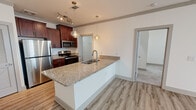 Located in Farragut, Tennessee, this single-floor residence offers a well-designed open-concept layout with contemporary finishes throughout. The kitchen serves as a central highlight, featuring rich cherry wood cabinetry, granite countertops, and a large central island with a built-in sink — ideal for both meal preparation and casual dining. Stainless steel appliances, including a refrigerator, range, and microwave, complement the space, while pendant lighting and a track light fixture add a modern, polished touch. Light wood-look flooring runs throughout the main living areas, lending a clean and cohesive aesthetic. The living area is bright and open, with natural light streaming in through windows and direct access to an outdoor balcony. Bedrooms are carpeted for comfort and equipped with ceiling fans; one bedroom offers a window with outdoor views and abundant natural light. The bathroom is thoughtfully finished with a dual-sink granite vanity, backlit mirrors, wood-tone cabinetry, tile-surround soaking tub, and wood-look tile flooring. A dedicated laundry area with hookups and wire shelving provides added convenience. Throughout the residence, neutral tones and clean lines create a fresh, move-in-ready atmosphere.