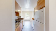 Located at 4816 San Pablo Dam Rd in El Sobrante, California, this 2-bedroom, 1-bathroom unit offers a well-organized single-floor layout designed for comfortable everyday living. Consistent light gray tile flooring runs throughout the home, providing a clean and cohesive aesthetic. The open living area is bright and airy, with textured ceilings, neutral white walls, and a window that brings in natural light. The galley-style kitchen is efficiently designed with warm wood cabinetry lining both sides, granite countertops, a stainless sink, and white appliances including a range and refrigerator. The primary bedroom is generously sized, featuring a large dual-panel closet for ample storage and easy access to the kitchen. The second bedroom offers a bright window with neighborhood views, a baseboard heater, and its own closet with bifold doors. The bathroom is well-appointed with tile flooring, a wood vanity topped with granite counters, a large mirror, and a glass-enclosed walk-in shower with marble-style tile surround and a window for ventilation. Together, these features create a functional and comfortable living space in a convenient East Bay location.