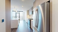 Located at 1331 Columbia Street in downtown San Diego, this modern one-bedroom, one-bathroom residence offers a thoughtfully designed layout with contemporary finishes throughout. The open-concept kitchen and living area serves as the heart of the space, showcasing light wood cabinetry that extends to the ceiling, a large waterfall-edge island with pendant lighting, and a full suite of stainless steel appliances including a gas range, built-in microwave, and French door refrigerator. Dark hardwood-style flooring runs continuously throughout, anchoring the clean, neutral palette. Floor-to-ceiling windows and a glass sliding door in the living area flood the space with natural light while framing sweeping elevated views of the San Diego skyline. The bedroom is bright and well-proportioned, with its own access to a private balcony and expansive city views through large glass doors. A dedicated walk-in closet features built-in shelving and hanging rods for organized storage. The bathroom is finished with full-tile walls and flooring, a frameless glass walk-in shower with a built-in niche, floating wood shelves, and backlit mirrors, delivering a clean, spa-inspired aesthetic. Recessed lighting and a crisp white ceiling complete the modern, elevated feel of this well-appointed urban residence.