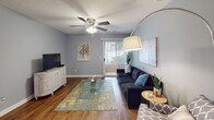 Located at 4600 Big Tree Way in Greensboro, North Carolina, this single-floor residence offers a well-organized layout with a comfortable and cohesive design throughout. The interior is finished with warm hardwood-style flooring that runs through the main living areas, complemented by cool gray walls that create a calm, neutral ambiance.

The living room is an inviting space featuring a ceiling fan, a textured ceiling, and a sliding glass door with vertical blinds that allows natural light to flow in while providing outdoor access. The room comfortably accommodates a seating area and entertainment setup, making it ideal for everyday living.

The galley-style kitchen is efficiently designed with white cabinetry, granite-look countertops, a stainless steel sink, and a full suite of black and stainless appliances including a refrigerator, range, and dishwasher. The hardwood-style flooring continues here, maintaining a consistent aesthetic throughout.

The bedroom is a spacious retreat with plush carpeting, a textured ceiling, a walk-in closet, and a sliding glass door offering views and access to the outdoors. The room is well-lit and provides ample space for a full bedroom suite.

The bathroom features a tub-shower combination with a curved curtain rod, wood-style flooring, and clean white fixtures, completing this well-appointed single-floor home.