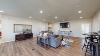 Located at 1030 S Chelton Rd in Colorado Springs, Colorado, this single-floor home offers a well-designed open layout that promotes a comfortable and functional living experience. The great room serves as the heart of the home, featuring warm wood-look flooring throughout, recessed lighting, and neutral-toned walls that create a bright, welcoming atmosphere. The generously sized living area provides ample space for multiple seating arrangements and entertainment, with a wall-mounted flat-screen television as a central focal point. The open flow connects seamlessly to additional areas of the home, enhancing the sense of spaciousness. The kitchen is thoughtfully appointed with crisp white shaker-style cabinetry, granite-look countertops, and a full suite of stainless steel appliances including a refrigerator, range, and dishwasher. A window above the sink allows natural light to fill the kitchen, while a dedicated dining area adjacent to the kitchen provides a practical space for everyday meals. The consistent wood-look flooring carried throughout the home ties each area together cohesively. The overall design balances modern finishes with a warm, casual aesthetic, making this Colorado Springs home a comfortable and move-in-ready space.