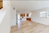 This well-designed three-story home offers 3 bedrooms, 3 bathrooms, and a thoughtful layout spread across three distinct levels. The ground floor houses an attached garage with a concrete floor and automatic opener, providing convenient interior access to the main living areas above.

The main living level serves as the heart of the home, featuring an open-concept layout that seamlessly connects the living room and kitchen. The kitchen is a standout space, outfitted with warm wood cabinetry, a white center island, stainless steel appliances, pendant lighting, and recessed ceiling lights. Light hardwood flooring flows throughout, complementing the clean white walls and creating a bright, airy atmosphere. A sliding glass door opens to a private balcony, allowing abundant natural light to fill the space.

The upper floor is dedicated to the bedrooms and bathrooms. The generously sized primary bedroom offers a comfortable retreat with a walk-in closet featuring wire shelving. The bathrooms are finished with modern fixtures, including undermount sinks set in stone-look countertops atop wood-toned vanities with large mirrors. Additional bedrooms are bright and well-proportioned, each with light hardwood floors and windows offering neighborhood views. Two closets and two hallways round out the home's practical and polished interior design.