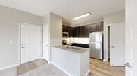 Located at 5284 Avery Rd in Columbus, Ohio, this single-floor unit offers a well-designed, open layout with thoughtful finishes throughout. The kitchen is a standout feature, showcasing rich dark-espresso cabinetry, granite countertops, a classic white subway tile backsplash, and a full suite of stainless steel appliances including a refrigerator, range, microwave, and dishwasher. A peninsula with an integrated sink provides additional prep space and a natural transition into the adjacent living area. The living room is generously proportioned, finished with plush carpet and neutral-toned walls, and opens directly onto a private balcony through sliding glass doors, bringing in natural light and outdoor views. The bedroom is comfortably sized, carpeted, and includes a ceiling fan and a window overlooking green surroundings. A dedicated walk-in closet off the bathroom offers ample organized storage with wire shelving. The bathroom features dark cabinetry with a light countertop, complemented by light wood-look flooring that carries through the kitchen and bathroom areas. The overall ambiance is clean, contemporary, and move-in ready, with a neutral color palette that creates a bright and cohesive feel throughout the space.