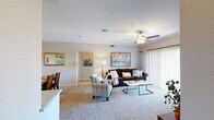 This single-floor residence offers a thoughtfully arranged layout that balances comfort and functionality across several distinct living spaces. The living room serves as the heart of the home, featuring plush wall-to-wall carpeting, crown molding, a ceiling fan with light fixture, and a gas fireplace framed by a clean white mantel. Sliding glass doors with vertical blinds open to a private outdoor balcony, allowing natural light to fill the room. A dedicated dining area adjacent to the living space accommodates a full-sized dining table and is accented with crown molding and framed wall art.

The kitchen is equipped with light wood cabinetry extending to the ceiling, ample countertop workspace, a double-basin sink, a full suite of white appliances including a range, over-the-range microwave, and refrigerator, as well as wood-look flooring for easy maintenance.

The bedrooms are carpeted and well-lit, each featuring a ceiling fan, vertical blinds, and windows that bring in natural light. The bathroom includes a wide, full-width vanity mirror, a speckled countertop with an undermount sink, tiled shower-tub combination, and wood-look flooring, delivering a clean and practical design throughout.