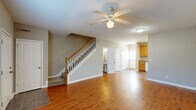 Located at 233 Hays Mill Rd in Carrollton, GA, this two-story, 2-bedroom, 3-bathroom home offers a practical and comfortable layout spread across two well-proportioned floors. The main level welcomes you with a bright, open living room featuring rich hardwood-style flooring, a ceiling fan, and neutral gray walls that create a clean, airy atmosphere. Natural light filters in through slatted blinds on large windows, enhancing the sense of openness. A classic staircase with white balusters and a warm wood handrail connects both levels. The adjacent kitchen is well-appointed with warm honey-toned wood cabinetry, granite-style countertops, tile flooring, and white appliances including a range, dishwasher, and refrigerator. A bathroom is also conveniently located on the main floor. Upstairs, both bedrooms are carpeted and finished in warm neutral tones, each featuring ceiling fans, natural light from windows with blinds, and ample closet space with double-door closets. The bathrooms include tub/shower combinations with clean white surrounds. A hallway and dedicated closet round out the upper level. This home combines functional design with comfortable finishes throughout.