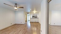 This single-floor residence offers a clean, modern aesthetic throughout, with warm hardwood-style flooring that flows seamlessly across the main living areas. The open-concept living space is bright and inviting, featuring a stylish ceiling fan with an integrated light fixture and recessed lighting that keeps the space well-illuminated. A large window allows natural light to fill the room, enhancing the airy atmosphere.

The kitchen is thoughtfully designed with a pass-through breakfast bar that opens to the living area, dark granite countertops with a mosaic tile backsplash, white cabinetry, and stainless steel appliances including a refrigerator, microwave, and range. A stainless steel undermount sink with a sleek modern faucet adds a polished touch, while directional track lighting overhead ensures excellent task illumination.

The bathroom is elegantly finished with white cabinetry, a vessel sink set atop a dark granite vanity, a framed mirror, and industrial-style wall sconces. The separate water closet features marble-style tile surround on the tub and shower walls, complemented by tile flooring throughout. The overall design of this space blends contemporary finishes with functional, efficient layout for comfortable everyday living.