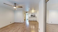 This single-floor residence offers a clean, modern aesthetic throughout, with warm hardwood-style flooring that flows seamlessly across the main living areas. The open-concept living space is bright and inviting, featuring a stylish ceiling fan with an integrated light fixture and recessed lighting that keeps the space well-illuminated. A large window allows natural light to fill the room, enhancing the airy atmosphere.

The kitchen is thoughtfully designed with a pass-through breakfast bar that opens to the living area, dark granite countertops with a mosaic tile backsplash, white cabinetry, and stainless steel appliances including a refrigerator, microwave, and range. A stainless steel undermount sink with a sleek modern faucet adds a polished touch, while directional track lighting overhead ensures excellent task illumination.

The bathroom is elegantly finished with white cabinetry, a vessel sink set atop a dark granite vanity, a framed mirror, and industrial-style wall sconces. The separate water closet features marble-style tile surround on the tub and shower walls, complemented by tile flooring throughout. The overall design of this space blends contemporary finishes with functional, efficient layout for comfortable everyday living.