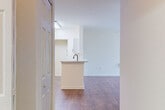 Located at 5018 26th St E in Bradenton, Florida, this single-story unit presents a clean, well-maintained interior defined by consistent wood-style flooring throughout and a neutral white color palette that creates a bright, open atmosphere. The main living area is generously proportioned, featuring crown molding, a ceiling fan, and an arched passageway that connects to additional spaces. A peninsula-style kitchen counter separates the living area from the kitchen, which is accented by a distinctive black industrial-style pendant light overhead. The kitchen itself includes white cabinetry and standard appliances.

The bedroom areas are well-sized, each benefiting from ceiling fans and large windows dressed with vertical blinds that allow ample natural light. Walk-in closets with wire shelving systems provide practical storage solutions. The bathroom is finished with wood-style flooring, a full tub and shower surround, a vanity with light stone-style countertop, and a large mirror. The floor plan flows in an open, connected manner, with six-panel interior doors and consistent finishes tying the space together for a cohesive, functional living environment.