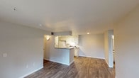 Located at 2700 W 103rd Ave in Federal Heights, Colorado, this single-floor residence offers a well-organized layout designed for comfortable everyday living. The open-concept living and dining area is anchored by rich wood-look flooring that flows throughout the main living spaces, creating a cohesive and inviting atmosphere. A peninsula-style kitchen features white cabinetry, dark countertops, a full suite of white appliances including an electric range and refrigerator, and a built-in sink — all illuminated by track lighting overhead. The kitchen opens directly to the living area, making it ideal for entertaining or daily interaction.

The living room extends toward a glass door and windows that invite natural light and provide outdoor views. Two carpeted bedrooms offer comfortable retreats, each with windows that bring in additional natural light. The bathrooms are cleanly finished with white tile tub-and-shower surrounds and chrome fixtures. A dedicated in-unit laundry area houses a full-size washer and dryer with overhead shelving, providing convenient storage. The overall design is neutral and clean, with light gray walls and white trim throughout, creating a bright and functional living environment.