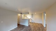 Located at 2700 W 103rd Ave in Federal Heights, Colorado, this single-floor residence offers a well-organized layout designed for comfortable everyday living. The open-concept living and dining area is anchored by rich wood-look flooring that flows throughout the main living spaces, creating a cohesive and inviting atmosphere. A peninsula-style kitchen features white cabinetry, dark countertops, a full suite of white appliances including an electric range and refrigerator, and a built-in sink — all illuminated by track lighting overhead. The kitchen opens directly to the living area, making it ideal for entertaining or daily interaction.

The living room extends toward a glass door and windows that invite natural light and provide outdoor views. Two carpeted bedrooms offer comfortable retreats, each with windows that bring in additional natural light. The bathrooms are cleanly finished with white tile tub-and-shower surrounds and chrome fixtures. A dedicated in-unit laundry area houses a full-size washer and dryer with overhead shelving, providing convenient storage. The overall design is neutral and clean, with light gray walls and white trim throughout, creating a bright and functional living environment.