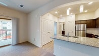 This single-story residence is thoughtfully designed with a modern aesthetic and cohesive finishes throughout. The open-concept kitchen serves as a central hub, showcasing dark espresso cabinetry, granite countertops, a subway tile backsplash, and a full suite of stainless steel appliances including a range, microwave, and refrigerator. A peninsula island with seating provides both additional prep space and a casual dining option, illuminated by pendant lighting overhead. Light wood-style flooring flows through the kitchen and main living areas, contributing to a clean, contemporary feel.

The living room is bright and inviting, featuring a sliding glass door that opens to an outdoor patio with exterior views, allowing natural light to fill the space. The layout connects seamlessly to the rest of the home through an arched entryway.

Multiple carpeted bedrooms offer comfortable retreats, each with closet space and room for generous furnishings. The primary bathroom features a dual-sink vanity with granite countertops, dark cabinetry, and a large mirror. A secondary bathroom includes a shower-tub combination, granite countertop vanity, and wood-style tile flooring, maintaining the consistent finish palette found throughout the home.