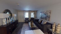 Located at 2825 W Walnut Hill Ln in Irving, Texas, this single-floor residence presents a cohesive, contemporary interior with consistent design elements throughout. The living room serves as the focal point of the space, featuring dark hardwood-style flooring, neutral-toned walls, and natural light admitted through double windows dressed with grommet-panel curtains and horizontal blinds. A large-format abstract canvas anchors the main wall, complementing the dark upholstered sofa, leather accent chairs, and a chrome arc floor lamp that add a modern, curated character to the room. A console table with a decorative mirror completes the entryway area.

The dining area transitions naturally from the living space, centered around a round table beneath a brushed-nickel multi-globe chandelier. The kitchen features white shaker-style cabinetry, light stone-look countertops, a stainless sink, and a dishwasher, with hardwood-style flooring continuing throughout.

The bedroom is well-proportioned, offering a ceiling fan with light fixture, a window with sheer curtains, and dark hardwood-style flooring. The bathroom includes white cabinetry, a framed vanity mirror, a marble-look countertop, and a tall storage tower, providing practical storage within a clean, bright finish.