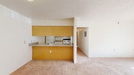 This single-floor, 2-bedroom, 1-bathroom unit in Fenton, Michigan offers a practical and functional layout designed for comfortable everyday living. The open-concept living and dining area greets you upon entry, featuring wall-to-wall carpeting, baseboard heating, and a textured ceiling that carries throughout the home. Natural light filters in through multiple windows, keeping the shared spaces bright and welcoming.

The kitchen is defined by a built-in peninsula with warm wood-toned cabinetry above and below, providing generous storage and a pass-through counter that connects seamlessly to the dining and living area. The kitchen is equipped with a range and refrigerator, keeping essentials within easy reach.

The primary bedroom is a well-proportioned retreat featuring two windows that invite natural light and views of the surrounding greenery, a ceiling fan with light fixture, and baseboard heating. A second bedroom offers similar comforts, including a window and closet access. Both bedrooms benefit from the two closets present throughout the unit, ensuring ample storage.

The full bathroom includes a tub and shower combination with clean white finishes. Consistent carpeting, neutral wall tones, and warm wood-accented doors and cabinetry lend a cohesive, understated character to the entire home.