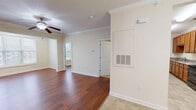 Located at 1010 S Fork Village Dr in Cramerton, NC, this one-bedroom, one-bathroom residence offers a thoughtfully laid-out single-floor plan. Warm hardwood-style flooring flows through the living room and bedroom, while light tile covers the kitchen, dining, and bathroom areas. Crown molding adds a classic finishing touch throughout the main living spaces.

The open living room is bright and comfortable, featuring a ceiling fan with light fixture and clean, neutral walls that lend themselves to a variety of décor styles. Adjacent to the living area, the dining space is defined by elegant chair rail molding and a brushed nickel chandelier, creating a refined atmosphere. The front entry door opens directly into this area, offering a welcoming arrival.

The kitchen is equipped with warm-toned wood cabinetry, granite-look countertops, a double stainless steel sink, and black appliances including a range, built-in microwave, and refrigerator — providing ample functionality and storage.

The bedroom is generously sized with natural light from a large window with blinds and direct access to both a closet and the bathroom. The bathroom includes a combination tub and shower, tile flooring, and grab bars for added convenience. A dedicated laundry area with washer and dryer hookups completes this practical and well-appointed residence.