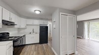 This single-floor, 2-bedroom residence at 5546 Scranton Rd in Hamburg, NY offers a well-organized and efficiently designed layout. The space is finished throughout with warm wood-look vinyl flooring and neutral gray walls, creating a clean, cohesive aesthetic from room to room.

The kitchen is a functional highlight, featuring white shaker-style cabinetry, white tile backsplash, light countertops, and black appliances including a refrigerator, electric range with overhead exhaust, and dishwasher. A stainless steel sink and ample cabinet storage complete this practical cooking space. Adjacent to the kitchen is a dedicated dining area with distinctive wainscoting-style wall paneling, adding a subtle architectural detail.

The living room is open and versatile, with a half-wall partition separating it from the entry area, which includes a louvered bi-fold closet door for added storage. Both bedrooms are comfortably sized — the primary bedroom being notably spacious — and each features baseboard heating, natural light from windows with blinds, and easy closet access. One bedroom also includes a wall-mounted air conditioning unit.

The entrance provides a welcoming transition into the home. Overall, the space presents a clean, updated interior well-suited for comfortable everyday living.