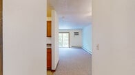 Located on the third floor at 2824 Grand Ave in Des Moines, Iowa, this one-bedroom, one-bathroom unit offers a practical and comfortable layout across a single floor. The generously sized bedroom is carpeted and features warm neutral walls, baseboard heating, a wall-mounted air conditioning unit, and a sliding glass door that opens to a private balcony overlooking lush greenery — bringing in abundant natural light and outdoor views. The open living and kitchen area is efficiently arranged, featuring wood-toned cabinetry, a white range, and tile flooring that transitions seamlessly into the carpeted living space. A hallway connects the main living areas to the full bathroom and a dedicated closet, providing practical storage. The bathroom includes a combination tub and shower, warm-toned tile flooring, and wood-fronted vanity cabinetry with ample under-sink storage. Throughout the unit, warm wood trim and doors add a classic touch, while textured ceilings and flush-mount lighting contribute to the overall functional design. This unit offers a straightforward, well-organized floor plan well-suited for efficient single-occupancy living in a central Des Moines location.