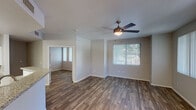 This single-floor residence is thoughtfully designed with a consistent, modern aesthetic carried throughout its living spaces. Rich wood-style flooring flows continuously across the main living areas, bedrooms, and entryway, lending warmth and visual cohesion to the layout.

The open-concept kitchen is a functional highlight, featuring white cabinetry, granite-look countertops, a subway tile backsplash, and black appliances including a range, refrigerator, and built-in microwave. A wraparound peninsula counter provides additional workspace and serves as a natural divider between the kitchen and the living area.

The living and dining areas are bright and airy, benefiting from multiple windows dressed with vertical blinds that allow for adjustable natural light. Ceiling fans with integrated lighting are installed in the main living space and additional rooms, promoting comfort and airflow. A sliding glass door in one of the rooms opens to an outdoor area, further connecting the interior to the outside.

The bedrooms offer clean, neutral walls and the same wood-style flooring. The bathrooms include granite-top vanities, tile-surround tub and shower combinations, and wood-look flooring. A dedicated water closet provides added privacy in one of the bathrooms. The entryway features a six-panel front door flanked by a large window, creating a welcoming and well-lit arrival experience.