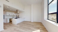Located at 165 Richards St in West Haven, CT, this modern 2-bedroom, 1-bathroom unit offers a thoughtfully designed single-floor layout with clean, contemporary finishes throughout. Light hardwood flooring runs continuously across the open-concept living and kitchen area, creating a bright, cohesive aesthetic. The kitchen is a standout feature, equipped with white shaker cabinetry with matte black hardware, striking veined quartz countertops, a center island with a gas cooktop and overhead range hood, stainless steel appliances including a refrigerator and dishwasher, and a black pull-down faucet over a stainless undermount sink. A bright hallway connects the living area to the two bedrooms and bathroom, with natural light streaming in through oversized black-framed windows at the end of the corridor. The bedrooms each feature large black-framed windows offering views of the surrounding neighborhood and tree canopy, filling the rooms with abundant natural light. Three closets provide generous storage throughout the unit. The bathroom features a marble-look quartz vanity, a lighted oval mirror, tile wainscoting, and light tile flooring. An in-unit laundry area adds everyday convenience to this well-appointed modern residence.