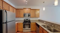 This single-floor residence offers a well-designed layout with two bedrooms and two full bathrooms. The open-concept living and kitchen area serves as the heart of the home, where warm hardwood-style flooring extends throughout the main living space. The kitchen is thoughtfully appointed with granite countertops, warm-toned wood cabinetry, and a full suite of stainless steel appliances, including a refrigerator, range, microwave, and dishwasher. A peninsula counter with a granite top separates the kitchen from the living area, providing additional prep space and a natural gathering point. Pendant lighting and track lighting illuminate the kitchen, adding both function and style.

Both bedrooms feature plush neutral carpeting, ceiling fans with light fixtures, and windows fitted with blinds that allow for natural light control. Each room offers a calm, comfortable atmosphere with clean white walls and generous proportions.

The two bathrooms are consistent in finish, each featuring granite-topped wood vanities, tile flooring, and a bathtub/shower combination. Additional storage is provided via wall-mounted cabinetry in one bathroom. Overall, the residence presents a cohesive, well-finished interior with practical and attractive design details throughout.