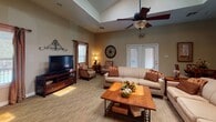Located at 128 Chestnut Ridge Dr in Harrisonburg, Virginia, this single-floor home offers a well-organized and comfortable layout designed for everyday living. The centerpiece of the home is the spacious living room, which boasts soaring vaulted ceilings with a skylight that floods the space with natural light. A ceiling fan adds to the comfort of the room, while a classic fireplace with a decorative mantel serves as a focal point. French doors lead to the exterior, enhancing the sense of openness, and multiple windows allow for additional natural light throughout. The living area provides ample room for seating and entertainment. Adjacent to the living room, the dining area offers an intimate setting with carpeted flooring, neutral-toned walls, and window treatments that provide both style and privacy. The kitchen is outfitted with warm wood cabinetry, dark granite-style countertops, and stainless steel appliances including a full-size refrigerator and dishwasher, complemented by a microwave and a double sink. The bold accent wall adds a warm, inviting character to the kitchen space. Overall, the home presents a cohesive and functional design with warm tones, carpeted living areas, and tile flooring in the kitchen.
