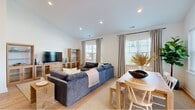 This thoughtfully designed single-story home features 4 bedrooms and 2 bathrooms, offering a generous and functional layout ideal for comfortable living. Light hardwood flooring flows seamlessly throughout, lending warmth and continuity to every room.

The entry hallway makes an immediate impression with a built-in console shelf, a large round mirror, and coastal-inspired artwork. It opens into a spacious living area with soaring vaulted ceilings, recessed lighting, and abundant natural light streaming through multiple windows. The living room comfortably accommodates large-scale furnishings and transitions naturally into the dining area, which benefits from additional window views.

The kitchen is well-appointed with gray shaker cabinetry, stainless steel appliances, a white subway tile backsplash, and a central island with bar seating beneath an industrial-style pendant light. A pantry provides added storage convenience.

The primary bedroom is generously sized, featuring multiple windows that bring in natural light and create an airy, serene atmosphere. Both bathrooms are stylishly finished — one with herringbone-patterned tile flooring, a tub-shower combination with elegant tilework, and matte black fixtures; the other with dual round mirrors and gray cabinetry.

A dedicated laundry room with full-size washer and dryer, two hallways, and two closets complete this well-organized and cohesive home.