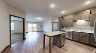 Located at 2407 CR-74 in Saint Cloud, MN, this 2-bedroom, 2-bathroom unit offers a well-designed single-floor layout with a thoughtful mix of functionality and modern finishes. The open-concept kitchen and living area serves as the heart of the space, featuring rich dark-toned shaker-style cabinetry, granite countertops, stainless steel appliances including a refrigerator, range, microwave, and dishwasher, and a central island that provides additional prep and dining space. Durable wood-look luxury vinyl plank flooring extends throughout the main living areas, complementing the neutral color palette. The living room is bright and airy, with a sliding glass door that opens to a private balcony, allowing natural light to fill the space. Both bedrooms are carpeted for comfort, with the generously sized primary bedroom offering a dedicated closet and its own bathroom featuring a wide vanity with ample storage. The second bedroom is well-proportioned with a window for natural light. A second full bathroom and two closets provide excellent storage throughout. An in-unit laundry area houses a stacked washer and dryer, adding everyday convenience. The overall ambiance is clean, modern, and move-in ready.