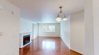 Located at 13503 97th Ave E in Puyallup, WA, this one-bedroom, one-bathroom residence offers a well-organized single-floor layout with a clean, neutral aesthetic throughout. The open-concept living room is a welcoming space anchored by a white-mantled fireplace and gleaming hardwood floors that reflect natural light streaming in through a large window. Vertical blinds along a sliding glass door add both privacy and easy access to the outdoors.

The kitchen is a functional highlight, featuring warm honey-toned cabinetry, tile backsplash, stainless steel appliances including a range, microwave, dishwasher, and refrigerator, and a center island with a tile countertop illuminated by dual pendant lights. Track lighting overhead enhances the kitchen's brightness and utility.

The bedroom is comfortably sized, finished with plush carpet, a window allowing natural light, and a dedicated closet for storage. The bathroom is straightforward and practical, with tile flooring, a full tub-shower combo, and clean white finishes throughout.

Overall, the space presents a bright, functional, and well-maintained living environment suitable for comfortable everyday living in the Puyallup area.