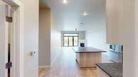 Located at 112 Papermill Run in Kimberly, Wisconsin, this well-appointed 2-bedroom, 2-bathroom single-floor residence offers a thoughtfully designed open-concept layout. The combined kitchen and living area serves as the heart of the home, featuring a large center island topped with dark granite countertops, white shaker-style cabinetry, stainless steel appliances including a French door refrigerator and built-in microwave, and a stainless dishwasher. Light wood-look flooring flows throughout, complementing the neutral color palette. The living area is anchored by a corner fireplace with a clean, modern surround and is enhanced by a ceiling fan and sliding glass doors that open to a private balcony. The primary bedroom is generously sized, offering a large picture window with serene waterfront views, and is accompanied by a spacious walk-in closet with wire shelving. The second bedroom is bright and well-proportioned. Both bathrooms are finished with wood-look tile flooring, and at least one features a full tub-shower combination. A dedicated laundry room houses a full-size front-loading GE washer and dryer with overhead shelving. Two closets provide ample storage throughout the residence.