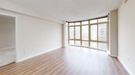Located in Silver Spring, Maryland, this well-appointed residence offers four bedrooms, two full bathrooms, and a thoughtfully designed layout across a single floor. The open living room is a standout feature, showcasing wide-plank hardwood-style flooring and expansive floor-to-ceiling windows that flood the space with natural light and frame views of the surrounding Silver Spring skyline and streetscape. The kitchen is fully equipped with light maple cabinetry, dark granite-style countertops, black appliances including a gas range, microwave, and refrigerator, and a skylight panel overhead — all set atop classic tile flooring. The four bedrooms are carpeted for comfort, each featuring large windows that bring in ample daylight and views of neighboring buildings. The primary bedroom includes mirrored sliding closet doors, adding a sense of depth and dimension. In total, five closets throughout the unit provide generous storage. Both bathrooms are finished with tile flooring, vanities with wooden cabinetry, and tub-shower combinations with white tile surrounds. Neutral tones and clean lines throughout create a calm, functional ambiance well-suited for everyday living in the heart of Silver Spring.