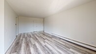 Located in White Bear Lake, Minnesota, this two-bedroom, one-bathroom unit offers a well-organized single-floor layout spanning a comfortable living area. The open-concept living, dining, and kitchen zone serves as the heart of the home, featuring modern light gray luxury vinyl plank flooring, a textured ceiling, and baseboard heating. A sliding glass door opens directly onto a private balcony, flooding the living space with natural light and providing outdoor views of the surrounding neighborhood and trees.

The kitchen is efficiently positioned adjacent to the living and dining areas, with white cabinetry and a white range, maintaining a clean and cohesive aesthetic throughout the common areas.

Both bedrooms are carpeted and bright, each featuring louvered bi-fold closet doors that provide generous storage. The primary bedroom is notably spacious and includes dual windows that bring in ample natural light, along with an extended wall of closet space. The second bedroom also features a closet and a sun-filled window.

The bathroom is finished with classic white subway-style wall tile, mosaic tile flooring, a wide vanity with under-sink cabinetry, and a large mirror with overhead lighting. Four total closets throughout the unit ensure plentiful storage. The unit presents a clean, neutral palette throughout.