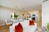 Located at 4896 Stellar Dr in Saint Cloud, FL, this contemporary two-story home offers 3 bedrooms, 5 bathrooms, and a thoughtfully designed layout spread across two floors. The main level opens into a bright, open-concept living, dining, and kitchen area finished with light wood-look flooring throughout. The kitchen features stainless steel appliances, two-tone cabinetry with wood grain lower cabinets and crisp white uppers, a clean quartz countertop, and an island with bar seating. The dining area benefits from natural light through large windows dressed in sheer curtains, while the living room provides a comfortable, airy gathering space. A well-appointed hallway on the main floor leads to a bathroom with a pedestal sink, adding convenience for guests. The attached garage offers additional storage and utility space. Upstairs, three bedrooms include a generously sized primary suite with an en-suite bathroom featuring a dual-sink vanity with wood-grain cabinetry and quartz countertops. Additional bedrooms are versatile and well-lit, with natural light from windows and ample closet space. With five bathrooms total, three dedicated closets, and two staircases, this home balances practicality and modern style in every detail.