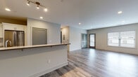 Located at 22 Washington Ave in Sandy Hook, Connecticut, this single-floor residence showcases a thoughtfully designed, modern interior with a cohesive palette of neutral tones and contemporary finishes throughout. The open-concept living and dining area serves as the heart of the home, featuring durable wood-look flooring in a soft gray hue, recessed lighting, and a peninsula with a dark wood countertop overhang that provides casual seating. Glass-panel doors lead to an exterior entry, while large windows allow natural light to pour into the generous living space. The kitchen is well-appointed with crisp white shaker cabinetry, quartz countertops, a tiled backsplash, and a full suite of stainless steel appliances, including a range, microwave, and dishwasher. Two bathrooms offer distinct yet complementary designs — one features a tub-shower combo with floor-to-ceiling tile and light marble-style flooring, while the other includes a walk-in glass-enclosed shower, a dark-toned vanity, and a white quartz countertop. The bedrooms are bright and airy, with wood-look flooring and multiple windows that frame views of the surrounding neighborhood. Clean lines and a neutral color scheme give the entire space a fresh, move-in-ready appeal.