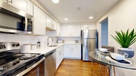 Located at 6260 Pearl Rd in Parma Heights, OH, this one-bedroom, one-bathroom unit offers a well-organized layout across a single floor. The kitchen is a standout feature, showcasing crisp white shaker-style cabinetry, light quartz countertops, a subway tile backsplash, and stainless steel appliances including a refrigerator, dishwasher, and range. Recessed lighting brightens the space, and warm hardwood-style flooring adds continuity throughout. Adjacent to the kitchen, the combined dining and living area is generously proportioned, with large sliding glass doors dressed in vertical blinds that allow abundant natural light to fill the room. The open flow between these spaces creates a comfortable, functional living environment. The bedroom offers a quiet retreat with a window fitted with horizontal blinds, warm flooring, and clean neutral walls. The bathroom features a full soaking tub with floor-to-ceiling large-format tile surround in a soft, textured neutral tone, lending a clean and modern aesthetic. A hallway connects the primary spaces, providing a practical and unobtrusive transition throughout the unit. Warm beige tones, consistent flooring, and thoughtful finishes give this residence a cohesive and move-in-ready appeal.