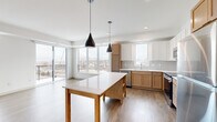 Located at 7570 32nd St N in Oakdale, Minnesota, this thoughtfully designed 2-bedroom, 3-bathroom residence offers a clean, modern aesthetic across a single level. The open-concept kitchen and living area serves as the heart of the home, featuring a two-toned cabinet design with warm wood lower cabinets and crisp white uppers, a white quartz countertop, subway tile backsplash, stainless steel appliances, and a central island with pendant lighting. Large windows and sliding glass door access to a private balcony flood the space with natural light and provide outdoor views. The living area is finished with wood-style luxury vinyl plank flooring and a vertical accent window that enhances the airy feel. Both bedrooms are carpeted and well-proportioned; the primary bedroom includes a spacious walk-in closet with wire shelving systems and direct access to a private bathroom with a wood-tone vanity, white countertop, and a glass-enclosed tub/shower. The second bedroom is comfortably sized with a large picture window overlooking the surrounding community. Three full bathrooms ensure ample convenience for residents and guests. Hallways connect the rooms efficiently, and clean white walls throughout contribute to the home's bright, contemporary character.