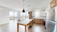 Located at 7570 32nd St N in Oakdale, Minnesota, this thoughtfully designed 2-bedroom, 3-bathroom residence offers a clean, modern aesthetic across a single level. The open-concept kitchen and living area serves as the heart of the home, featuring a two-toned cabinet design with warm wood lower cabinets and crisp white uppers, a white quartz countertop, subway tile backsplash, stainless steel appliances, and a central island with pendant lighting. Large windows and sliding glass door access to a private balcony flood the space with natural light and provide outdoor views. The living area is finished with wood-style luxury vinyl plank flooring and a vertical accent window that enhances the airy feel. Both bedrooms are carpeted and well-proportioned; the primary bedroom includes a spacious walk-in closet with wire shelving systems and direct access to a private bathroom with a wood-tone vanity, white countertop, and a glass-enclosed tub/shower. The second bedroom is comfortably sized with a large picture window overlooking the surrounding community. Three full bathrooms ensure ample convenience for residents and guests. Hallways connect the rooms efficiently, and clean white walls throughout contribute to the home's bright, contemporary character.