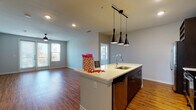 This single-floor residence showcases a thoughtfully designed open-concept layout that seamlessly connects the kitchen and living areas. The kitchen serves as the centerpiece, anchored by a large island with a light quartz countertop, an undermount sink, and a trio of sleek black pendant lights suspended overhead. Dark espresso cabinetry lines the kitchen walls, complemented by stainless steel appliances, a mosaic tile backsplash, and recessed lighting, creating a polished, contemporary aesthetic. Warm hardwood-style flooring flows throughout the main living areas, enhancing the sense of openness and continuity.

The living area is generously proportioned, featuring a ceiling fan, multiple windows, and glass-paneled doors that invite abundant natural light. A private balcony is accessible from this space, extending the living area outdoors.

The bedrooms are finished with plush carpeting and ceiling fans, each offering natural light through blinded windows. One bedroom features direct access to an en-suite bathroom. The bathrooms are finished with large-format dark slate tile flooring, dark cabinetry with extended vanities, and glass-enclosed showers, projecting a refined, spa-like atmosphere throughout.