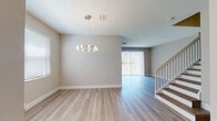 This well-appointed two-story home offers a clean, contemporary design with light hardwood-style flooring flowing seamlessly throughout both levels. The open main floor features a spacious living and dining area bathed in natural light from large sliding glass doors dressed with vertical blinds. A modern ring chandelier serves as a focal point in the dining area, complementing the bright, neutral palette of warm beige walls and white trim.

The kitchen is thoughtfully designed with two-tone cabinetry — white upper cabinets paired with warm wood-finish lower cabinets — topped with quartz countertops and a subtle gray tile backsplash. Stainless steel appliances, including a range, over-the-range microwave, and dishwasher, complete the functional and stylish space. A sliding glass door in the kitchen opens directly to an outdoor area with green views beyond.

Both bathrooms are finished with elegant marble-look tile on the floors and walls. One bathroom features a glass-enclosed walk-in shower, while the other offers a full soaking tub. Both include white vanities with quartz countertops and gold-toned hardware accents.

The upper floor, accessible via a classic staircase with a white banister, includes well-sized bedrooms with large windows overlooking the surrounding greenery. A dedicated in-unit laundry room with a full-size washer and dryer and overhead wire shelving adds everyday convenience.