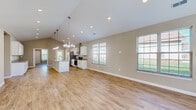 This single-story home offers a thoughtfully designed open-concept layout spread across a generously sized floor plan. The living area greets visitors with striking vaulted ceilings and a decorative front door with sidelights, allowing natural light to pour in. Large windows throughout maintain a bright, airy atmosphere and provide views of the surrounding exterior.

The kitchen and living room share a seamlessly connected space anchored by a central island with a granite countertop and integrated sink, complemented by white shaker cabinetry, matching granite counters along the perimeter, stainless steel appliances, a wall-mounted range hood, and pendant lighting above the island.

Light-toned luxury vinyl plank flooring runs throughout the main living areas, while the dedicated laundry room houses a full-size Whirlpool washer and dryer. The two bathrooms feature granite vanity tops, white cabinetry, and tub-shower combinations with wood-look flooring. The spacious primary bedroom includes a large walk-in closet with wire shelving systems. Additional bedrooms offer ceiling fans, natural light, and ample closet space, creating a functional and comfortable living environment throughout.