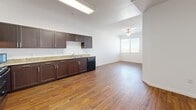 Located at 2675 W Agate Ave in Las Vegas, NV, this 2-bedroom, 1-bathroom unit offers a well-organized single-floor layout designed for comfortable everyday living. The open-concept kitchen and living area is anchored by warm wood-style flooring that runs throughout the main space. The kitchen is equipped with rich dark-brown cabinetry, granite-style countertops, a full suite of black appliances including a refrigerator, range, dishwasher, and microwave, along with ample upper and lower cabinet storage. The living area flows naturally from the kitchen and is brightened by a window and ceiling fan, creating a light and airy atmosphere. Both bedrooms feature neutral carpet flooring and white walls that offer a clean, versatile canvas. The primary bedroom includes a sliding-door closet, while the second bedroom benefits from a window with views of the surrounding neighborhood and palm trees. The full bathroom is finished with the same dark cabinetry and granite countertop as the kitchen, complemented by a large vanity mirror, a bathtub, and wood-style flooring. A hallway connects the main living areas to the bedrooms, with a dedicated closet providing additional storage throughout this efficiently designed home.