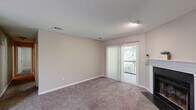 Located in Tradition Augusta, Augusta, GA, this single-floor, 3-bedroom, 1-bathroom residence offers a well-organized and functional layout. The living room serves as the heart of the home, showcasing a classic wood-burning fireplace framed by a clean white mantel, plush carpet flooring, and a sliding glass door that opens to a private balcony with lush tree views, filling the space with natural light. The galley-style kitchen is thoughtfully designed with white shaker cabinetry, marble-look countertops, a tasteful tile backsplash, and wood-look flooring. Black appliances including a range, microwave, and refrigerator complete the kitchen. The three bedrooms each feature soft carpet flooring and neutral walls, with the generously sized primary bedroom offering ample room for furnishings. The shared full bathroom is well-appointed with a marble-look vanity countertop, a vessel sink with brushed nickel fixtures, dual mirrors, and a tub-shower combination with wood-look tile flooring. Textured ceilings are present throughout, and the light, neutral color palette provides a calm and cohesive ambiance across every room.