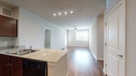 This single-floor residence offers a well-designed, open-concept layout that connects the kitchen and living areas seamlessly. The kitchen is a functional centerpiece, featuring rich, dark wood cabinetry with ample upper and lower storage, granite-style countertops, a peninsula with an integrated sink, and a full suite of black appliances including a refrigerator, range, built-in microwave, and dishwasher. Recessed lighting and track lighting illuminate the space effectively throughout. Wood-look flooring extends across the kitchen, living, and dining areas, providing a cohesive and easy-to-maintain surface. The living area is generously proportioned, benefiting from a ceiling fan and a large window that draws in natural light.

The bedrooms are carpeted for comfort, each featuring windows with blinds and ceiling fans to promote airflow. The unit includes two bathrooms, both finished with dark wood vanities, light countertops, and wood-look flooring. One bathroom features a combined tub and shower, while the other includes a dedicated walk-in closet with wire shelving, providing practical storage solutions. The neutral color palette throughout creates a clean, move-in ready environment suitable for a variety of interior styles.