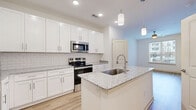 This 560 square foot, one-bedroom apartment in Glen Allen, VA, offers a blend of efficiency and modern design. The single-floor layout maximizes space utilization, featuring an open-concept design that creates a sense of spaciousness. The kitchen is a standout, boasting crisp white cabinetry, stainless steel appliances, and a subway tile backsplash. A central island with a granite countertop provides additional prep space and casual dining options. The living area, while compact, benefits from large windows that flood the space with natural light. The bedroom, measuring 140 square feet, includes plush carpeting and ample closet space. The bathroom is well-appointed with a combination tub-shower, white vanity, and granite countertop. Throughout the apartment, warm wood-look flooring contrasts beautifully with the white walls and cabinetry, creating a fresh, contemporary aesthetic. Recessed lighting and modern fixtures add to the overall polished look. This apartment is ideal for those seeking a low-maintenance, high-style living space in a convenient location.