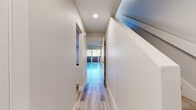 Located at 450 E Wilbur Rd in Thousand Oaks, CA, this two-story, 2-bedroom, 2-bathroom home offers a clean, modern aesthetic spread across two well-proportioned floors. Light wood-tone flooring runs throughout, complementing the neutral palette of crisp white walls and white trim, creating a bright and cohesive interior.

The main floor houses the kitchen, dining and living area, a bathroom, and hallway access. The kitchen is well-appointed with white shaker-style cabinetry, gray quartz countertops, a classic subway tile backsplash, and stainless steel appliances. The open hallway leads toward the living area and a balcony, providing outdoor access and natural light.

Upstairs, both bedrooms are generously sized with large windows that frame views of the surrounding neighborhood and greenery. The spacious primary bedroom includes recessed lighting and ample closet space. The bathrooms are finished in a clean, contemporary style featuring white cabinetry with dark countertops and a full tub-shower combination with brushed gold fixtures.

With five closets distributed across both floors, storage is plentiful. The staircase connects the two levels seamlessly, and recessed lighting throughout ensures a well-lit environment. This home offers a functional, modern layout in a desirable Thousand Oaks location.